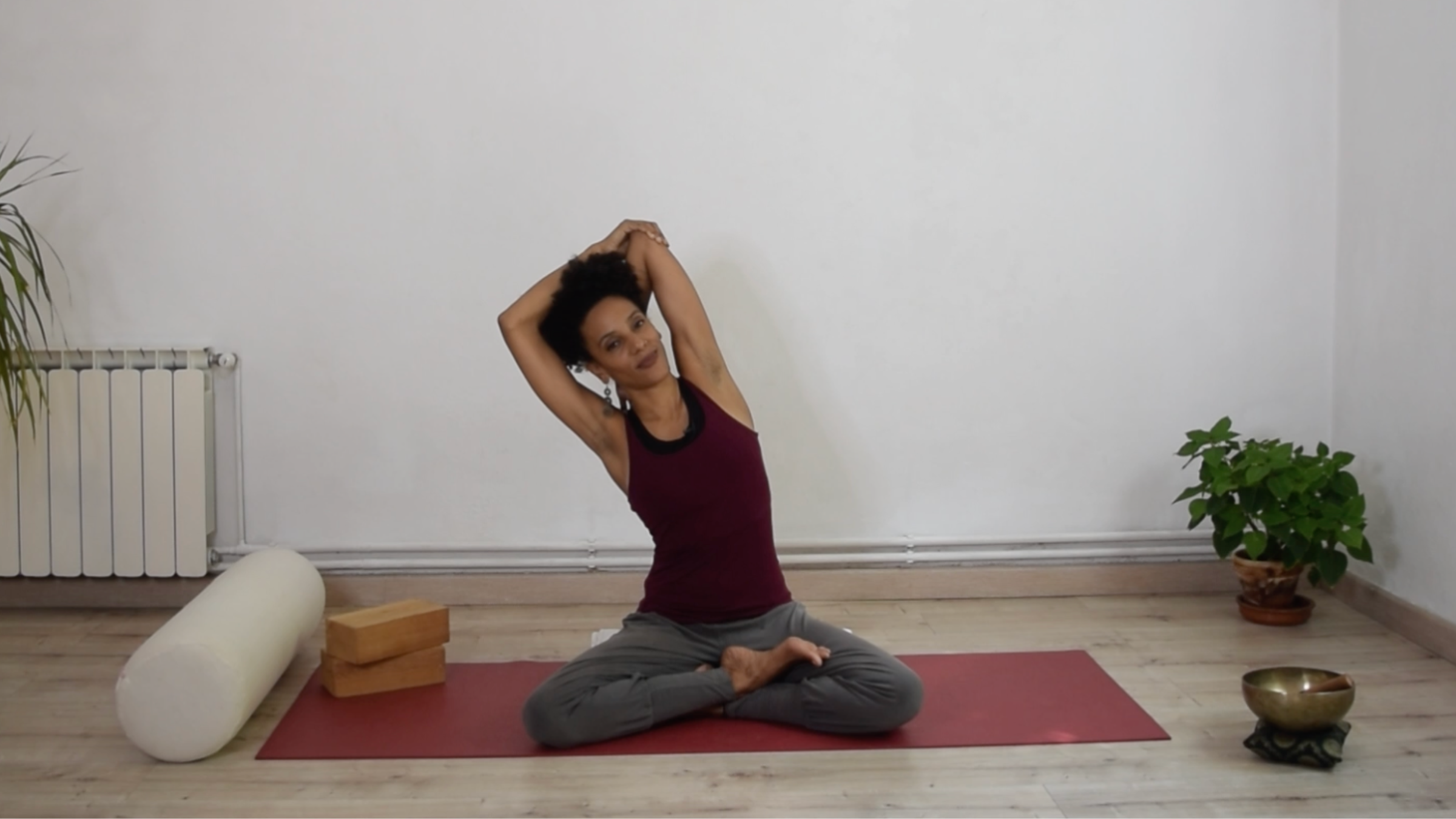 A seated practitioner leaning to the side with one elbow pointed toward the ceiling, holding the elbow with the opposite hand to stretch the side body.